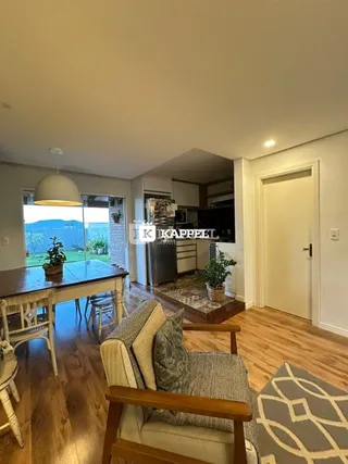 Uma sala de estar com piso de madeira e vista para a paisagem externa.