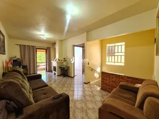 Sala de estar com sofás marrons e piso de cerâmica em um imóvel no Brasil.