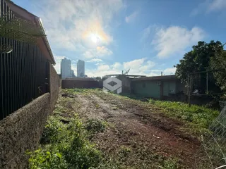 Vista externa de um terreno com vegetação densa e muros de vedação.