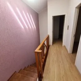 Foto de um corredor interno com parede texturizada e piso de madeira.