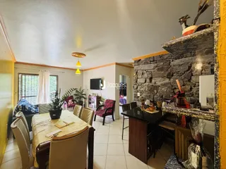 Sala de estar com mesa de jantar e parede de pedra em um imóvel em Lajeado.
