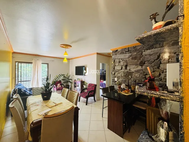 Sala de estar com mesa de jantar e parede de pedra em um imóvel em Lajeado.