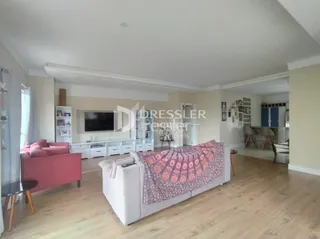 Uma sala de estar ampla com piso de madeira clara.