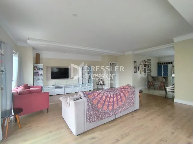 Uma sala de estar ampla com piso de madeira clara.