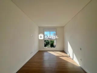 Vista de um corredor com piso de madeira e janela de grande porte.