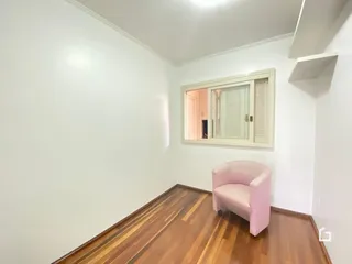 Ambiente interno de uma sala com piso de madeira e parede branca.