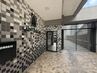 Foto do corredor de entrada de um edifício com revestimento de azulejos pretos e brancos.
