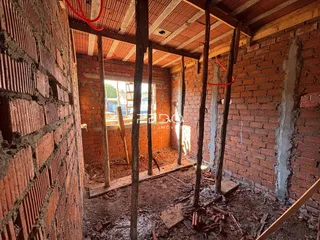 Interior de uma construção em reforma com paredes de tijolo expostas.