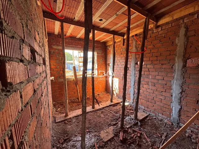 Interior de uma construção em reforma com paredes de tijolo expostas.