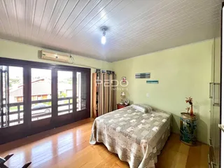 Quarto com piso de madeira e porta de vidro abrindo para o exterior.
