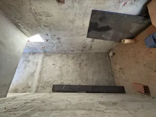 Interior de um espaço com paredes de concreto aparente e teto inacabado.