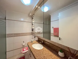 Banheiro com revestimento de cerâmica branca e bancada de granito.