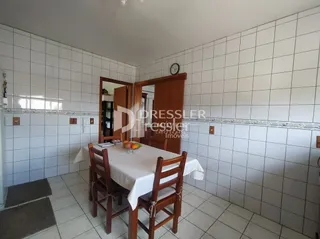 Uma mesa de jantar com cadeiras de madeira está no ambiente.
