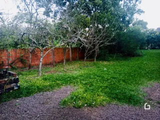 Vista externa do terreno com muro de tijolos e gramado.