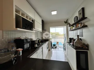 Cozinha moderna com armários brancos e vista para a área externa com piscina.
