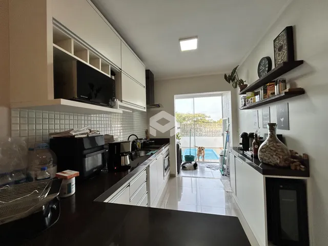 Cozinha moderna com armários brancos e vista para a área externa com piscina.