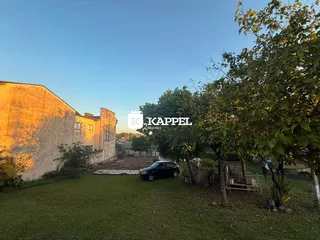 Vista externa de uma residência com gramado e vegetação.