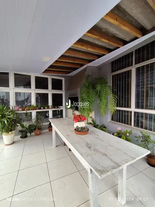 Vista de uma área comum com piso claro e mesa de madeira no interior de uma residência.