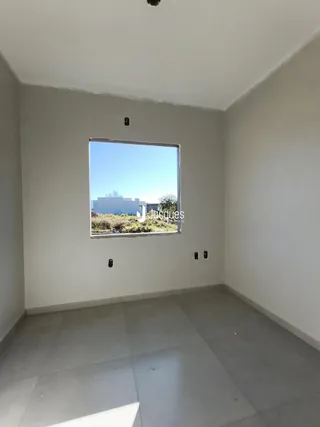 Vista de uma janela de um cômodo interno com paredes brancas.