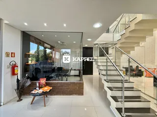 Vista do hall de entrada com sala de estar aberta e escada moderna.