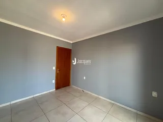Ambiente interno de uma sala com piso de cerâmica e porta de madeira.