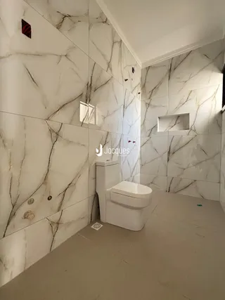 Interior de um banheiro com revestimento de mármore branco nas paredes.