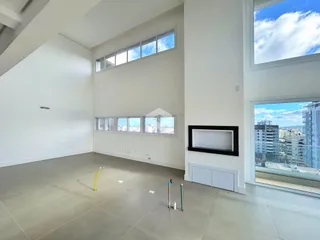 Ambiente interno de uma sala ampla com grandes janelas.