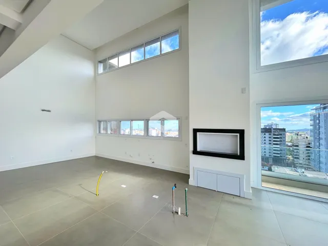 Ambiente interno de uma sala ampla com grandes janelas.