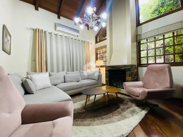 Sala de estar ampla com lareira e grandes janelas no imóvel.