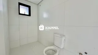 Foto de um banheiro com paredes e piso brancos e um vaso sanitário.