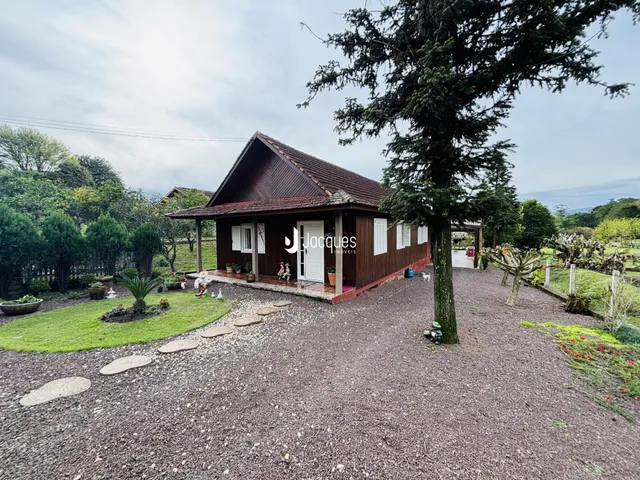 Fachada de uma casa de madeira em Lajeado, Brasil, com jardim e área de acesso em cascalho.