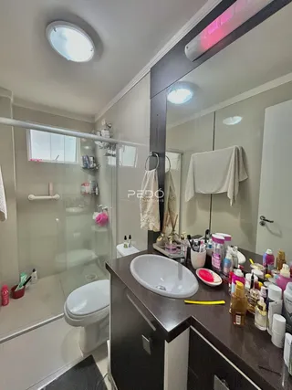 Foto de um banheiro com box de vidro e louças brancas.