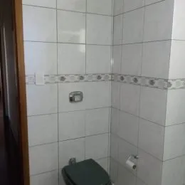 Foto de um banheiro com revestimento de azulejos brancos nas paredes.