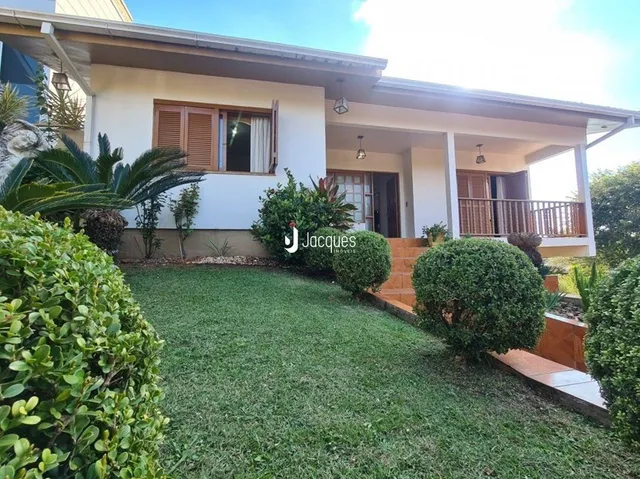 Jardim verde com vegetação na frente de uma residência.