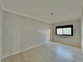 Vista interna de um ambiente com piso de madeira clara e paredes brancas.