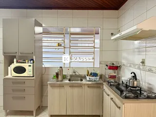 Foto da cozinha mostrando armários, bancada e fogão.