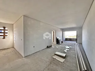 Interior de um cômodo em construção com paredes brancas e piso de concreto.