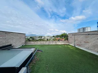 Quintal gramado com muros de tijolos e vista para a paisagem.