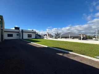 Vista da fachada de uma residência com jardim e área pavimentada.