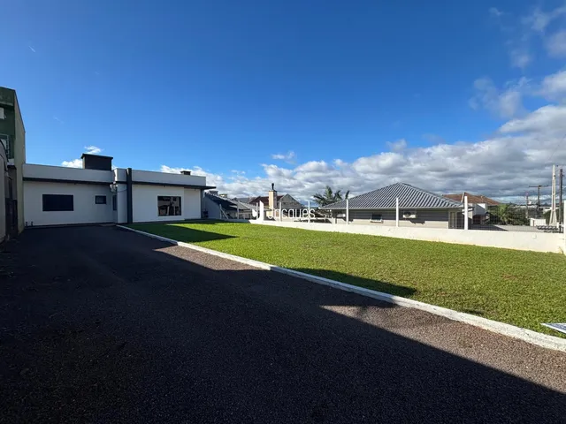 Vista da fachada de uma residência com jardim e área pavimentada.