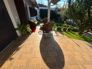 Vista de uma área externa com mobiliário de vime e jardim.