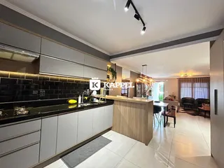 Cozinha moderna com armários escuros e bancadas pretas em um ambiente aberto.