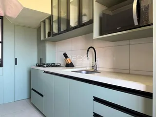 Cozinha moderna com armários e bancada claras.