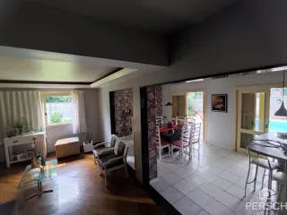 Sala de estar com piso de madeira e cortinas claras.