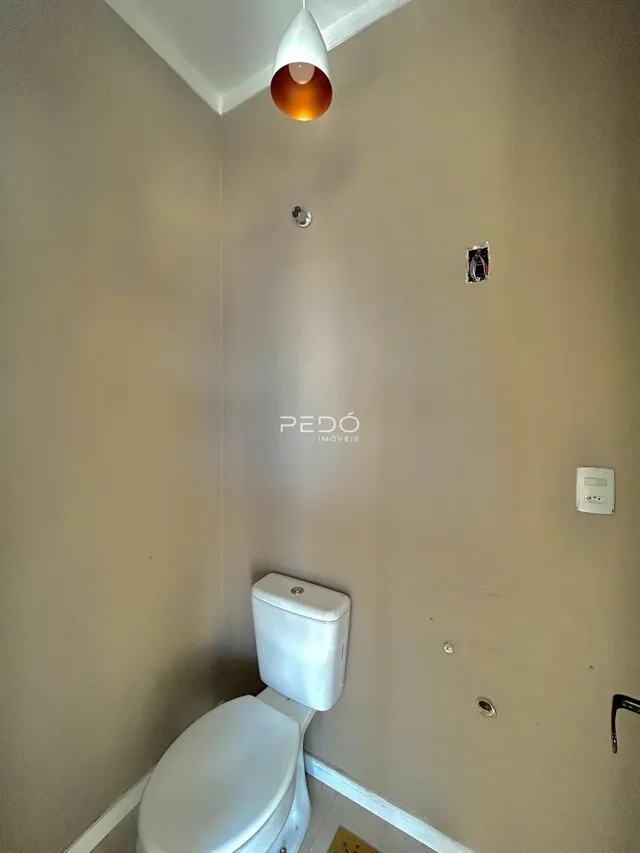 Foto de uma parede de banheiro com vaso sanitário e luminária.
