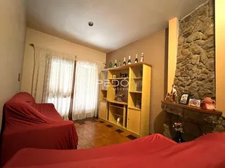 Sala de estar com piso de madeira e parede de pedra em um imóvel no Brasil.