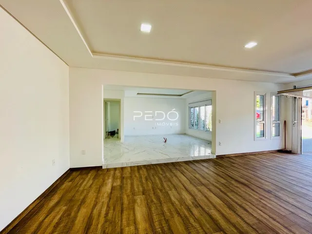 Vista de um ambiente interno com piso de madeira e abertura para outra sala.