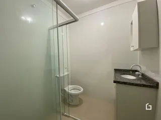 Foto de um banheiro com box de vidro e louças sanitárias.