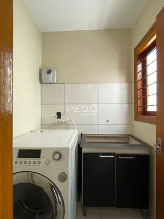 Foto de uma área de serviço com máquina de lavar e armários brancos.