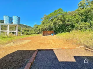 Paisagem externa de uma propriedade com vegetação densa ao fundo.